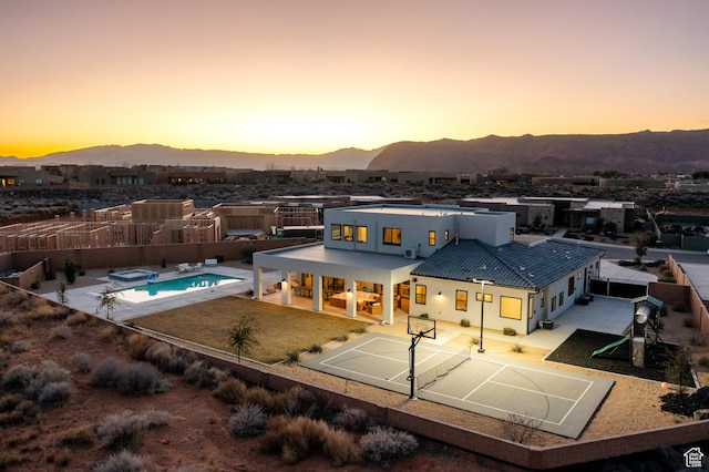 4862 N Sand Cove Cir, St George, UT 84770 - back house at dusk featuring a mountain view, basketball court, and a patio area