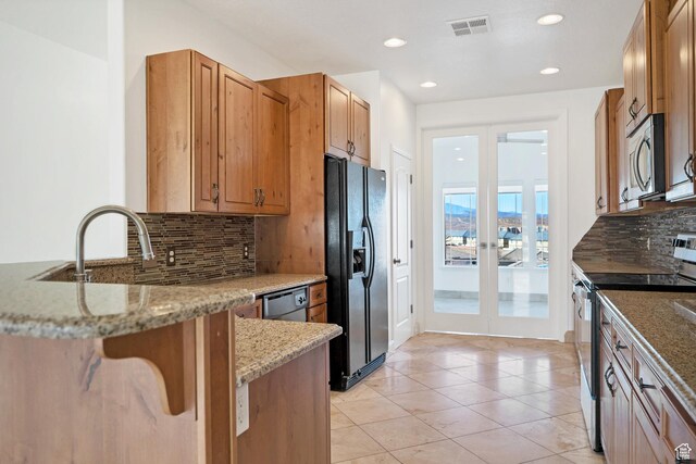 2261 S Tonaquint Dr Unit 8, St George, UT 84770 - kitchen featuring light tile patterned floors, appliances with stainless steel finishes, backsplash, light stone countertops, and kitchen peninsula