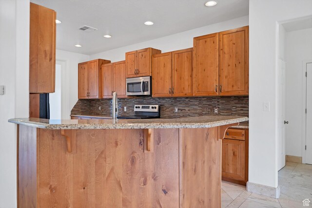 2261 S Tonaquint Dr Unit 8, St George, UT 84770 - kitchen with tasteful backsplash, a breakfast bar area, stainless steel appliances, and kitchen peninsula