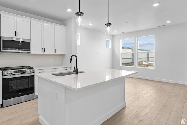 2869 S Ritter Row W Unit 54, West Valley City, UT 84128 - kitchen with pendant lighting, a center island with sink, stainless steel appliances, light countertops, and white cabinetry
