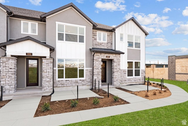 2869 S Ritter Row W Unit 54, West Valley City, UT 84128 - view of front facade with board and batten siding, stone siding, and fence