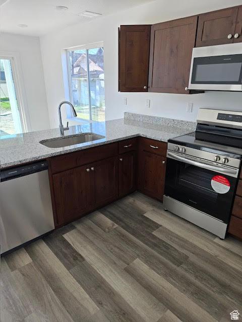 kitchen featuring dark hardwood / wood-style floors, appliances with stainless steel finishes, sink, and light stone counters