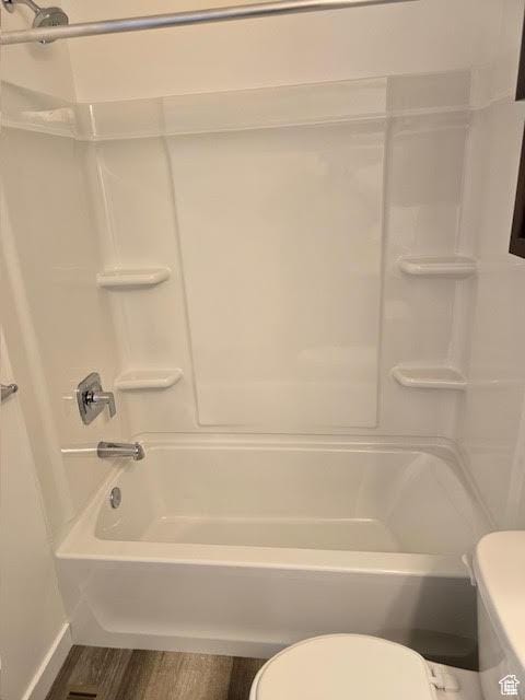 bathroom with wood-type flooring, tub / shower combination, and toilet