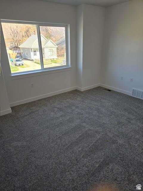 unfurnished room with dark colored carpet