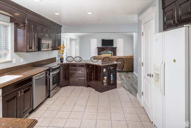 939 E Summit Dr N, Smithfield, UT 84335 - kitchen with stainless steel appliances, light tile patterned floors, and dark brown cabinetry