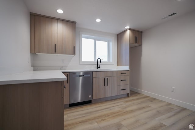 kitchen featuring sink, stainless steel dishwasher, light brown cabinetry, and light hardwood / wood-style floors