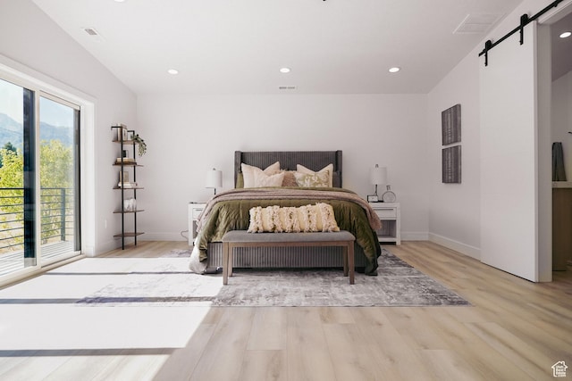 bedroom with a barn door and light wood-type flooring