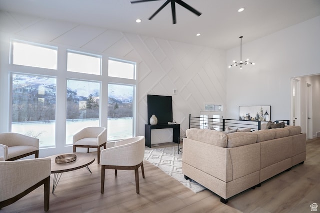 living room featuring a towering ceiling, a notable chandelier, and light hardwood / wood-style floors