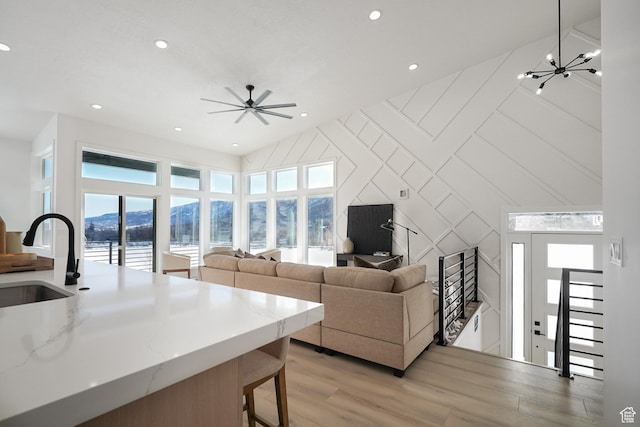 living room featuring sink, ceiling fan with notable chandelier, and light hardwood / wood-style floors