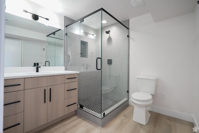 bathroom with vanity, hardwood / wood-style floors, a shower with door, and toilet