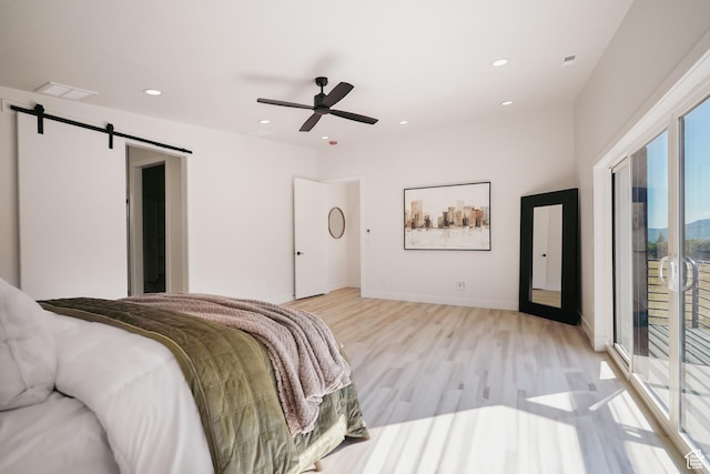 bedroom featuring access to exterior, light hardwood / wood-style flooring, a barn door, and ceiling fan