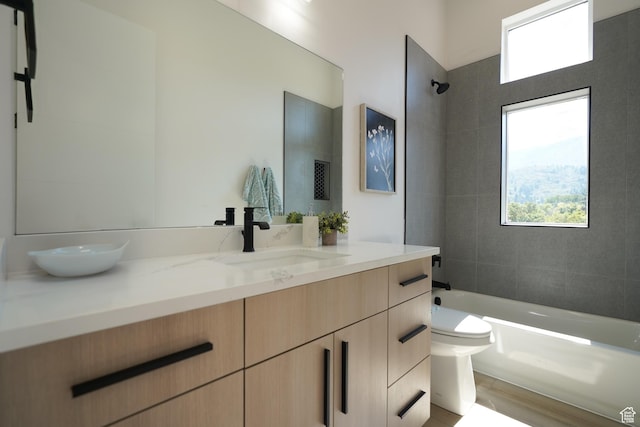 full bathroom with vanity, wood-type flooring, toilet, and tiled shower / bath