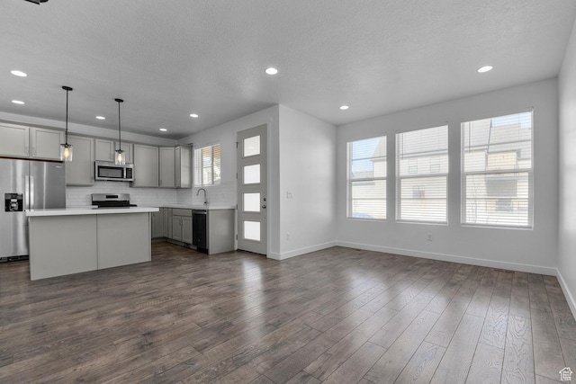 kitchen featuring gray cabinetry, decorative light fixtures, a center island, plenty of natural light, and appliances with stainless steel finishes
