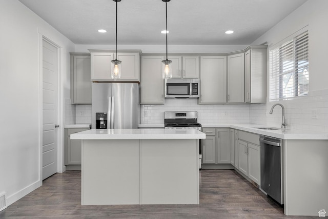 kitchen featuring pendant lighting, appliances with stainless steel finishes, gray cabinets, and sink