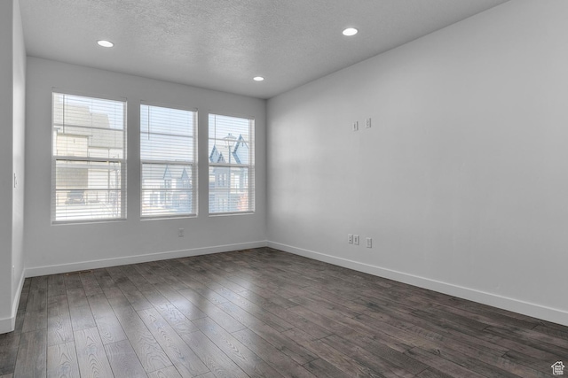 empty room with dark hardwood / wood-style floors and a textured ceiling