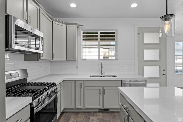 kitchen featuring pendant lighting, sink, stainless steel appliances, light stone counters, and decorative backsplash