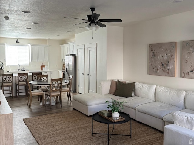 living room featuring light wood-style flooring, a textured ceiling, and ceiling fan