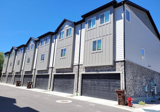 exterior space with a residential view, brick siding, board and batten siding, and an attached garage