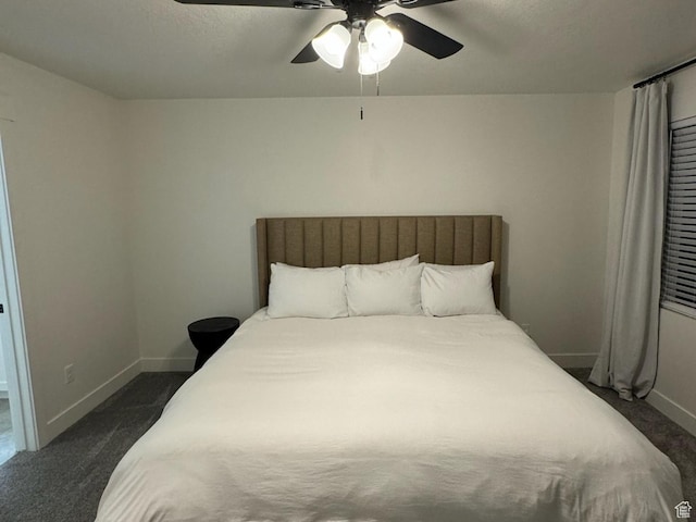 bedroom featuring a ceiling fan, baseboards, dark carpet, and a textured ceiling