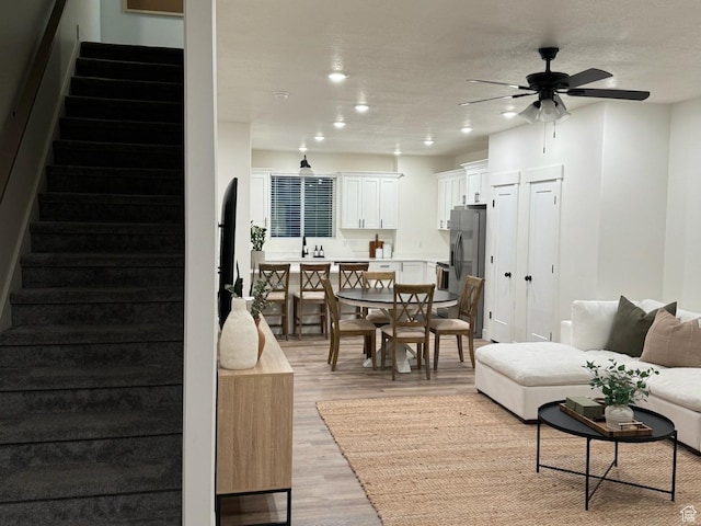 living room with light wood finished floors, recessed lighting, stairs, and a ceiling fan