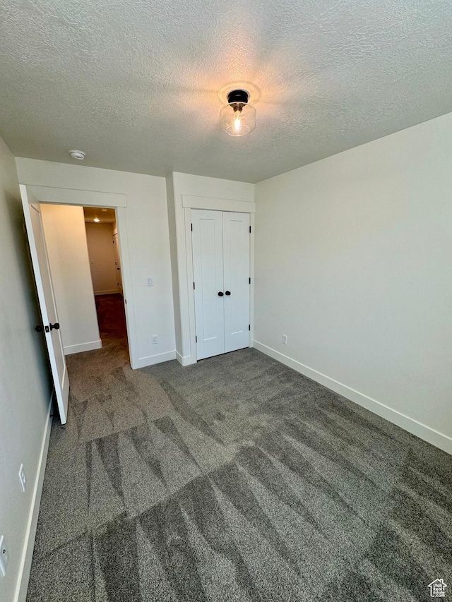 unfurnished bedroom featuring carpet, baseboards, a closet, and a textured ceiling