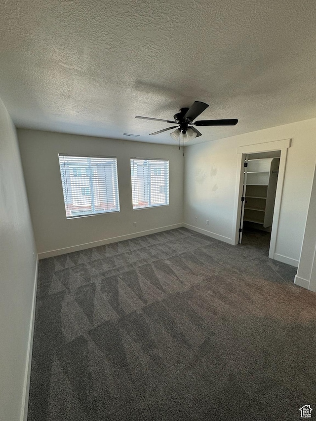 carpeted spare room featuring a textured ceiling, visible vents, baseboards, and ceiling fan