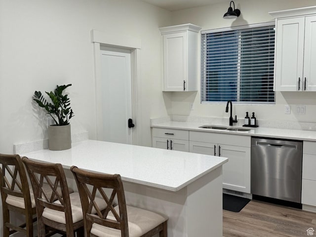kitchen featuring a sink, a peninsula, a breakfast bar, and stainless steel dishwasher