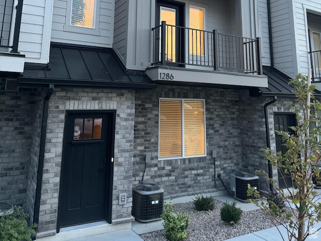 property entrance with metal roof, a balcony, central AC, and a standing seam roof