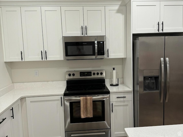 kitchen with stainless steel appliances, light stone countertops, and white cabinets