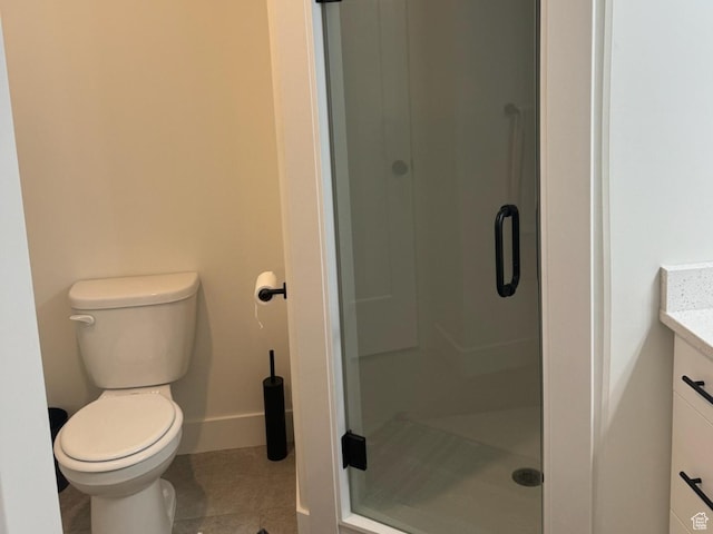 bathroom featuring tile patterned flooring, a shower stall, baseboards, toilet, and vanity