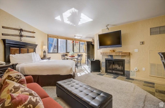 bedroom with a tile fireplace, vaulted ceiling, visible vents, and a textured wall