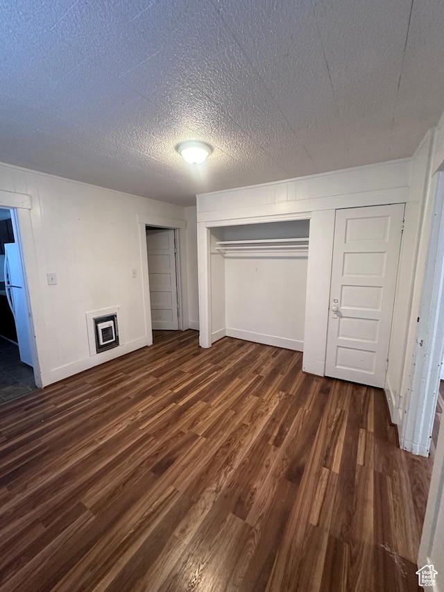 unfurnished bedroom with white refrigerator, dark wood-type flooring, and a textured ceiling