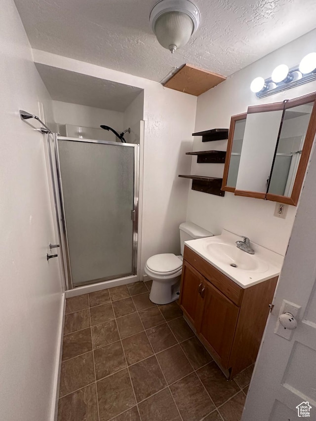 bathroom with vanity, toilet, a textured ceiling, and a shower with shower door