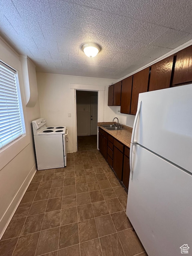kitchen featuring dark brown cabinets, sink, and white appliances