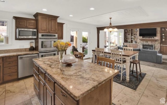 14548 S Rose Ave, Herriman, UT 84096 - kitchen featuring french doors, built in features, a kitchen island, stainless steel appliances, and a fireplace