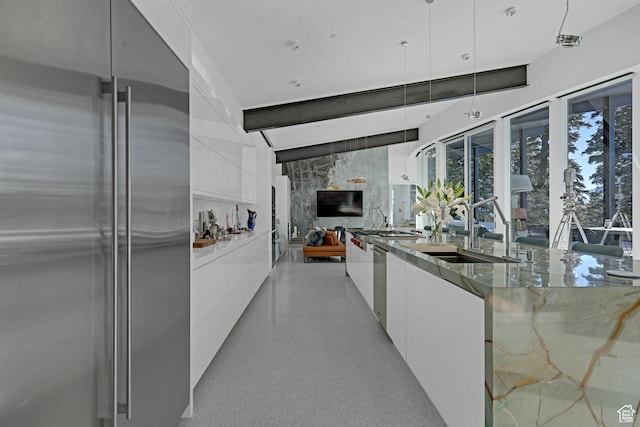 kitchen featuring stone counters, appliances with stainless steel finishes, sink, white cabinets, and hanging light fixtures