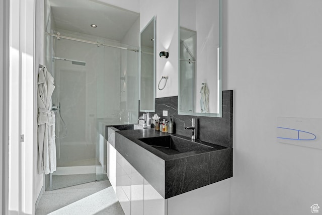 bathroom featuring tasteful backsplash, sink, and a shower with shower door