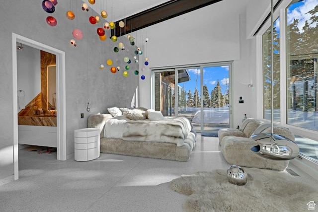 bedroom featuring multiple windows, access to exterior, and a towering ceiling