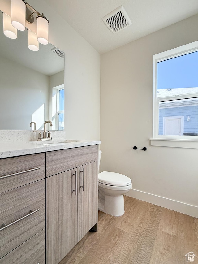 bathroom with vanity, visible vents, toilet, and wood finished floors