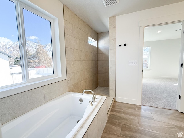 bathroom featuring visible vents, baseboards, and a garden tub