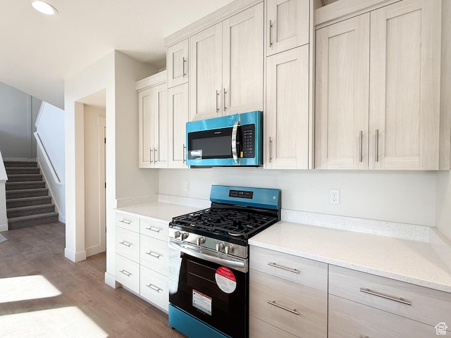 kitchen featuring light wood-type flooring, baseboards, recessed lighting, light stone countertops, and stainless steel appliances