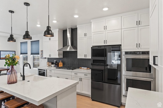 6850 Mountain Maple Dr Unit 14, Park City, UT 84098 - kitchen featuring pendant lighting, wall chimney range hood, sink, white cabinetry, and stainless steel appliances