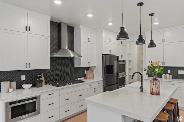 6850 Mountain Maple Dr Unit 14, Park City, UT 84098 - kitchen featuring wall chimney range hood, stainless steel appliances, an island with sink, white cabinets, and decorative backsplash