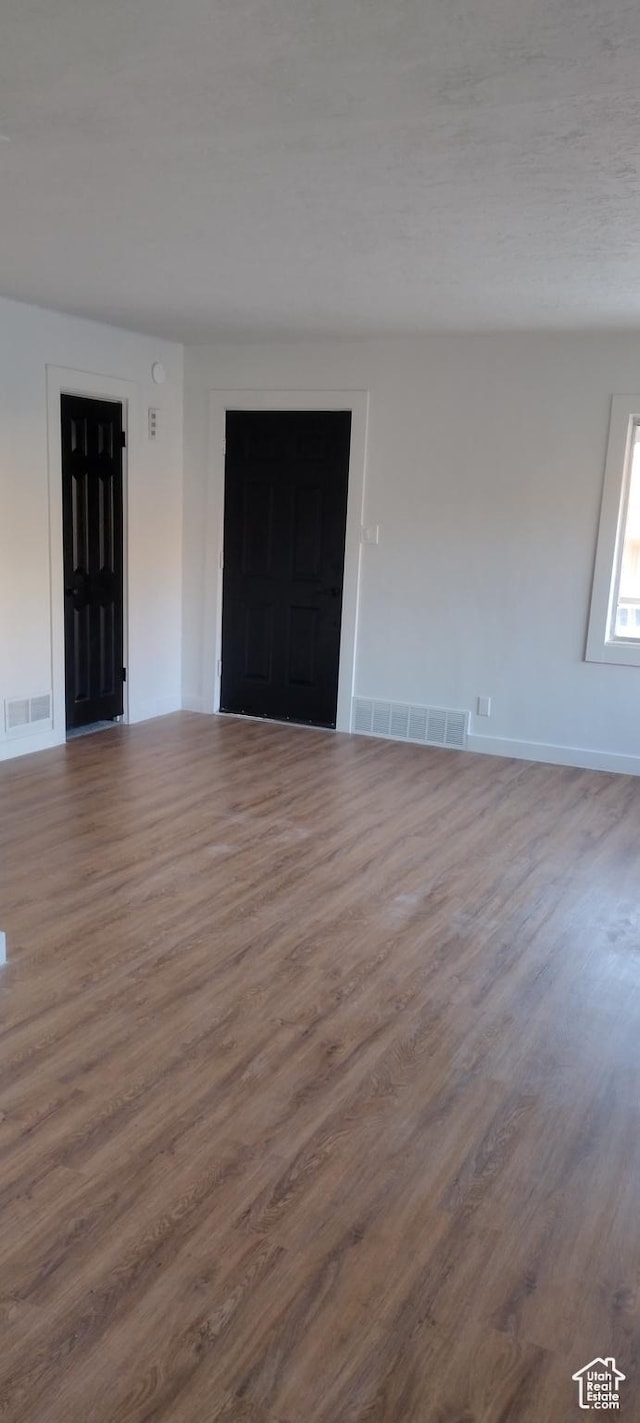 empty room with baseboards, visible vents, and wood finished floors