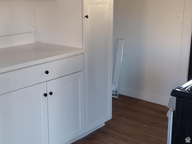kitchen with light countertops, baseboards, dark wood finished floors, electric range, and white cabinets