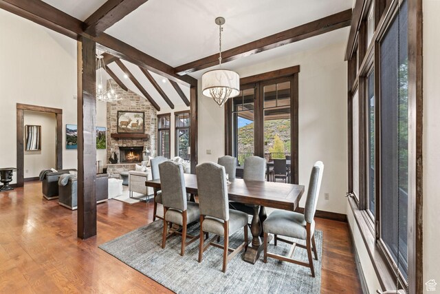 8670 Ranch Club Ct, Park City, UT 84098 - dining space with an inviting chandelier, a stone fireplace, hardwood / wood-style floors, and lofted ceiling with beams