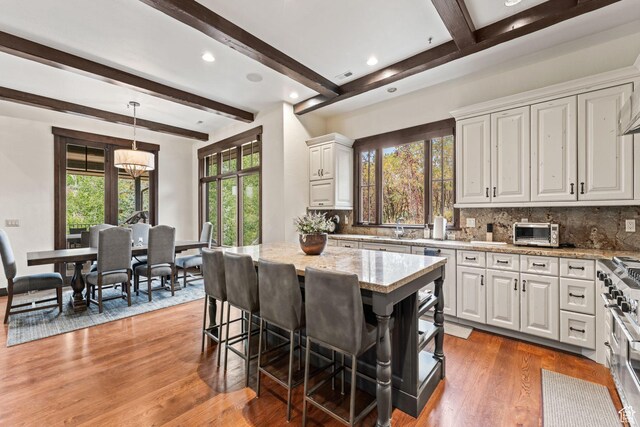 8670 Ranch Club Ct, Park City, UT 84098 - kitchen with a breakfast bar, white cabinetry, a kitchen island, pendant lighting, and light stone countertops
