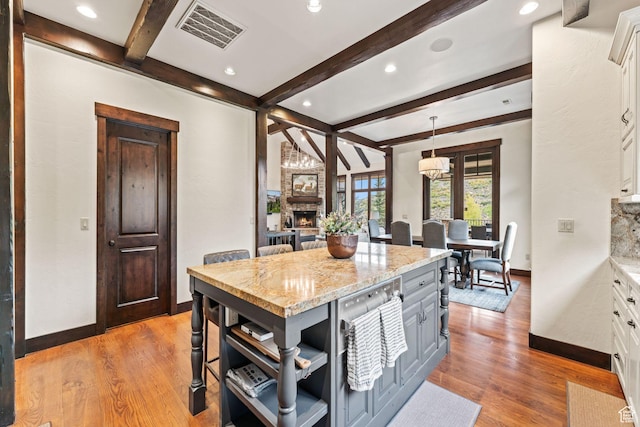 8670 Ranch Club Ct, Park City, UT 84098 - kitchen featuring a stone fireplace, decorative light fixtures, white cabinets, a center island, and light stone counters