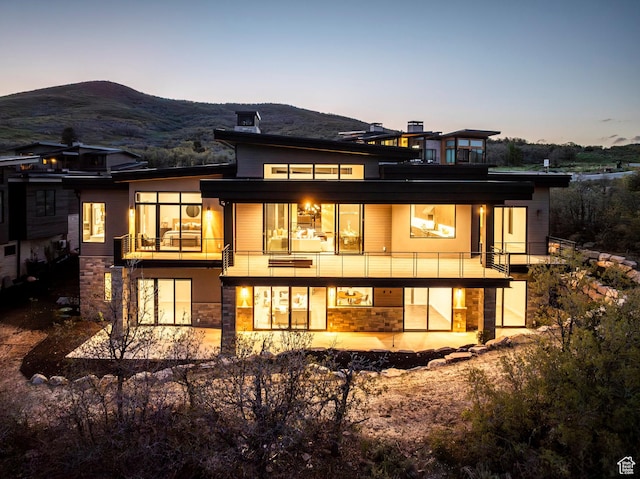 1817 W Skyridge Dr, Heber City, UT 84032 - back of property at dusk featuring a balcony, stone siding, and a mountain view