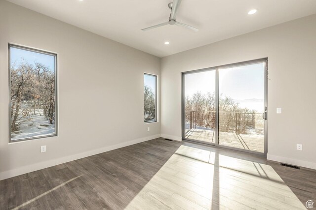 empty room featuring ceiling fan, dark hardwood / wood-style floors, and a healthy amount of sunlight